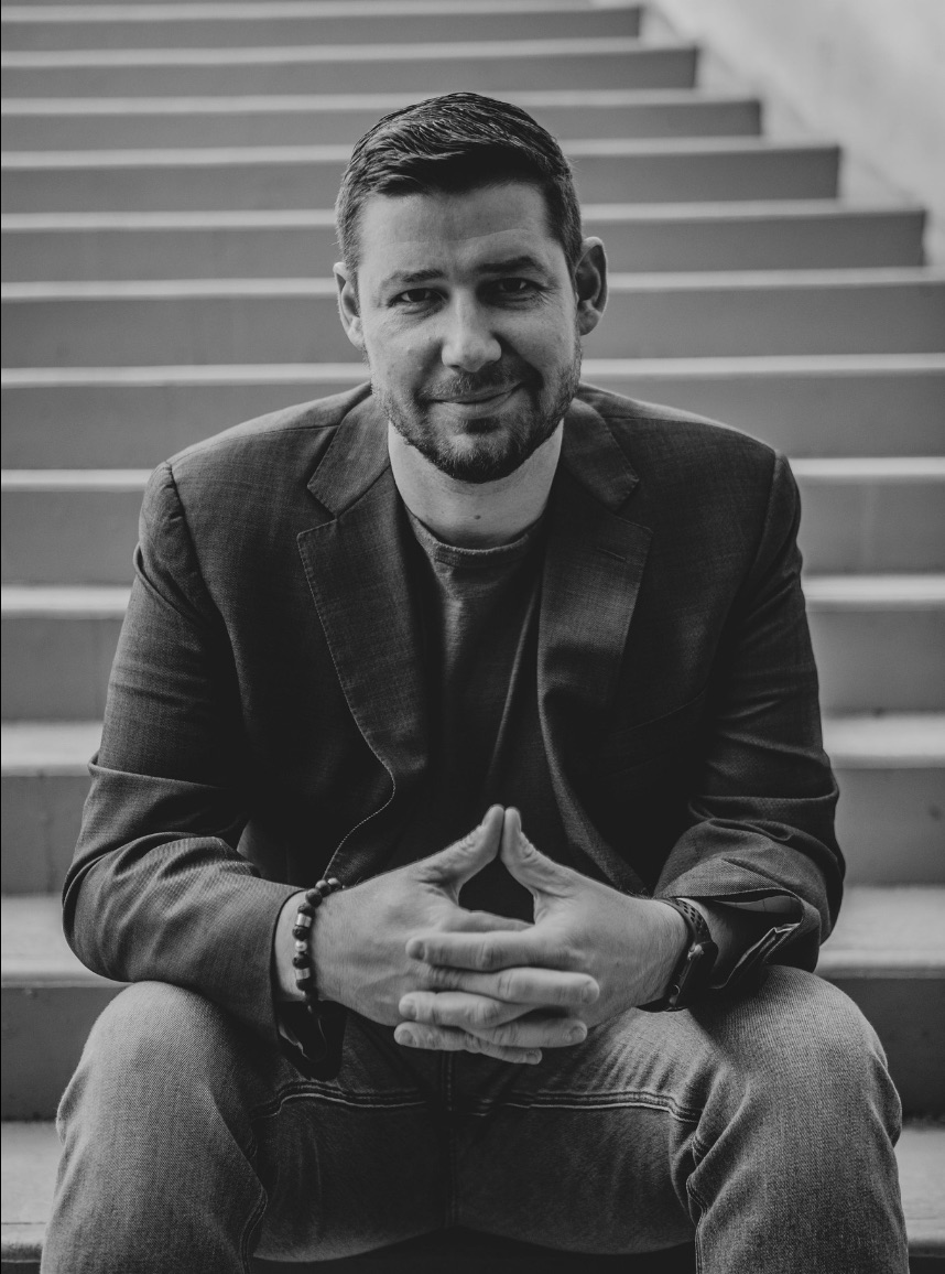 Black and white portrait of Jordan Thomson sitting on concrete steps