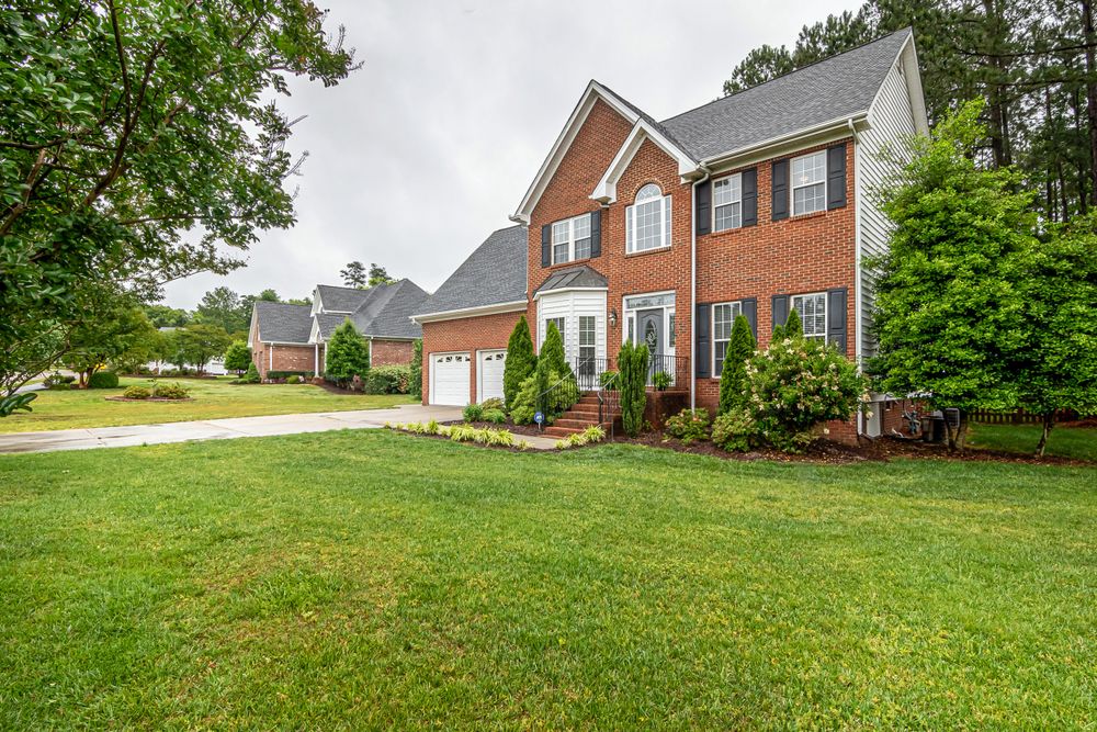 A brick two-storey single-family home with a mature green lawn