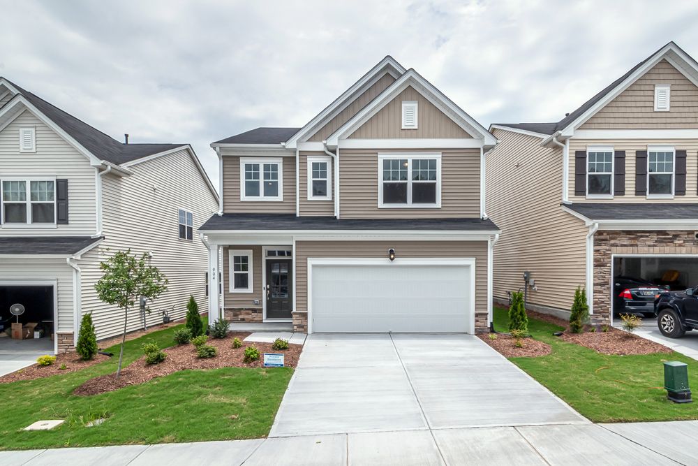A two-storey single-family home with a front garage and a green lawn